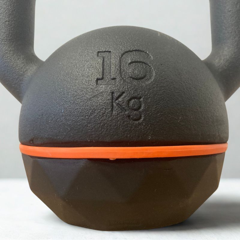 Na obrázku je detail na litinový kettlebell Domyos z Decathlonu. Na obrázku je vidět detail litinového zpracování.